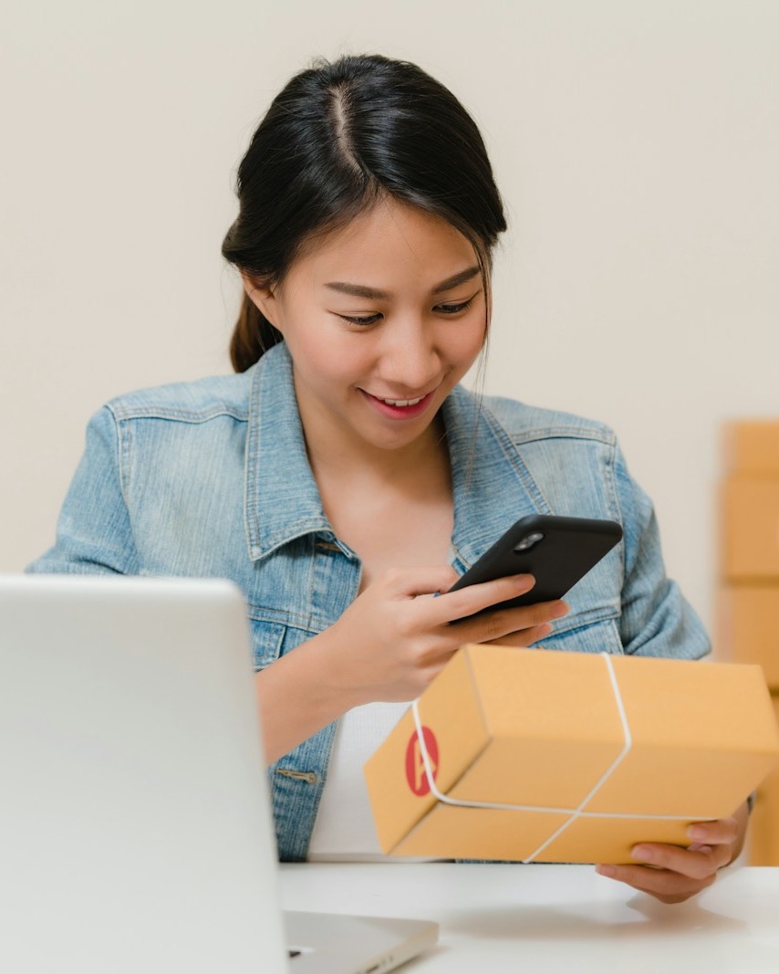 eCommerce seller checking an order on her phone while packing parcels